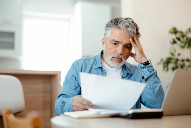 Stressed taxpayer reviewing overdue tax bills at a desk